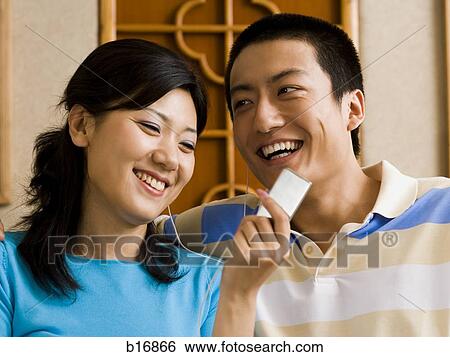Stock Photograph - Couple listening to MP3 player smiling. Fotosearch