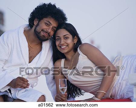 Couple sitting outdoors with champagne flutes smiling and snuggling View Large Photo Image Stock Image - Couple sitting outdoors with champagne flutes smiling and snuggling. Fotosearch