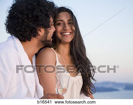 Couple sitting outdoors with champagne flutes and scenic background smiling and snuggling View Large Photo Image Stock Image - Couple sitting outdoors with champagne flutes and scenic background smiling and snuggling. Fotosearch
