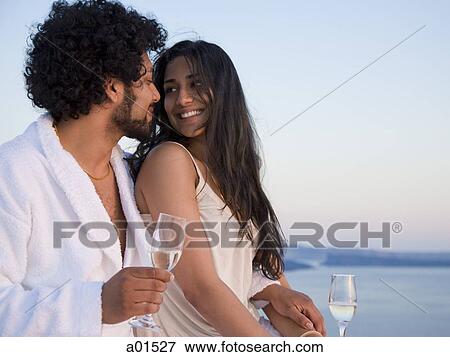 Couple sitting outdoors with champagne flutes and scenic background smiling and snuggling View Large Photo Image Stock Photo - Couple sitting outdoors with champagne flutes and scenic background smiling and snuggling. Fotosearch