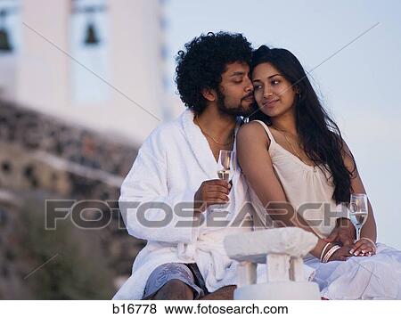 Couple sitting outdoors with champagne flutes and scenic background smiling and snuggling View Large Photo Image Stock Photo - Couple sitting outdoors with champagne flutes and scenic background smiling and snuggling. Fotosearch