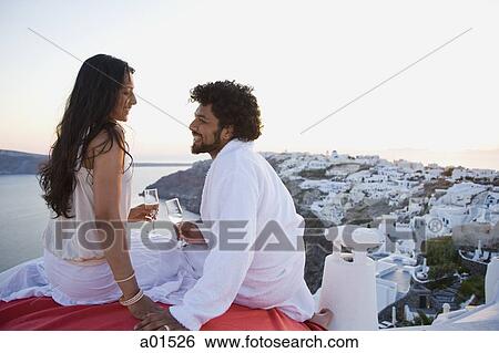 Couple sitting outdoors with champagne flutes and scenic background smiling View Large Photo Image Stock Photograph - Couple sitting outdoors with champagne flutes and scenic background smiling. Fotosearch