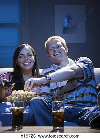 Couple with bowl of popcorn watching television smiling View Large Photo Image Stock Image - Couple with bowl of popcorn watching television smiling. Fotosearch