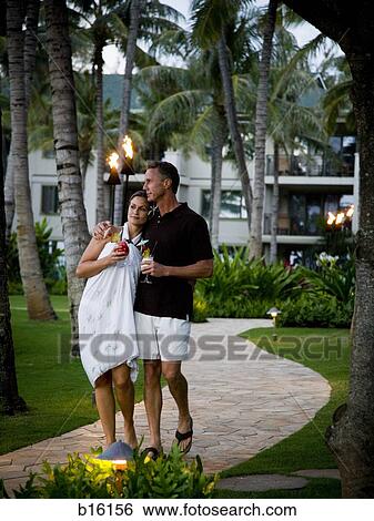 Couple with tropical cocktails walking at resort View Large Photo Image Stock Photograph - Couple with tropical cocktails walking at resort. Fotosearch