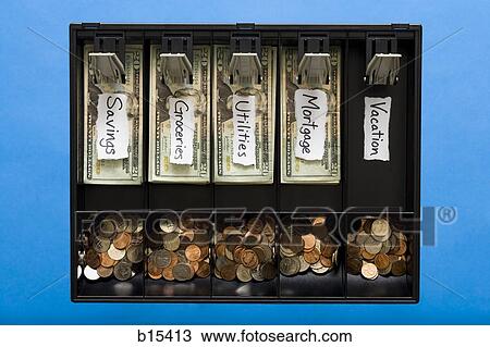 Stock Image - Detailed view of US currency and coins in till with labels for household expenses with no money for vacation. Fotosearch