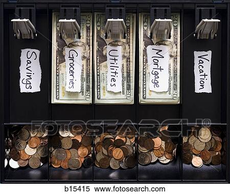 Stock Photography - Detailed view of US currency and coins in till with labels for household expenses with no vacation money or savings. Fotosearch