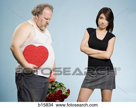 Disheveled man with heart box and red roses with disinterested woman View Large Photo Image Picture - Disheveled man with heart box and red roses with disinterested woman. Fotosearch