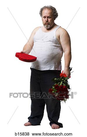 Stock Photo - Disheveled man with red roses and heart box frowning. Fotosearch
