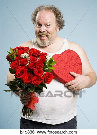Stock Photograph - Disheveled man with red roses and heart box smiling. Fotosearch
