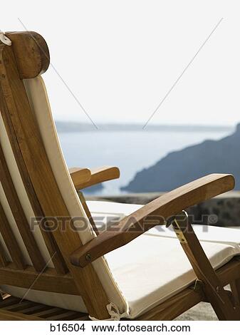 Empty wooden chair outdoors with water View Large Photo Image Picture - Empty wooden chair outdoors with water. Fotosearch
