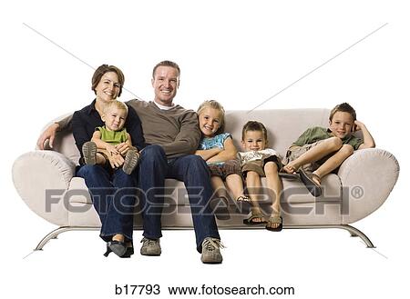 Stock Image - Family sitting on a couch smiling.. Fotosearch