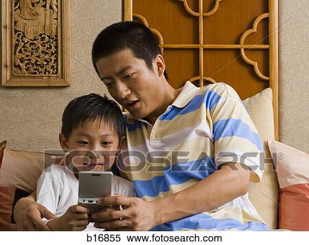Father and son looking at portable electronic device View Large Photo Image Stock Photography - Father and son looking at portable electronic device. Fotosearch