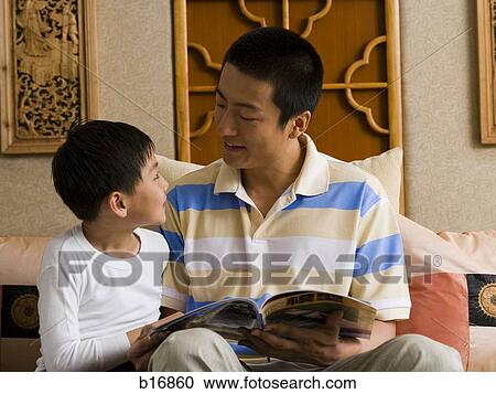 Stock Image - Father and son reading magazine. Fotosearch