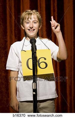 Girl contestant standing at microphone smiling and pointing up View Large Photo Image Stock Image - Girl contestant standing at microphone smiling and pointing up. Fotosearch