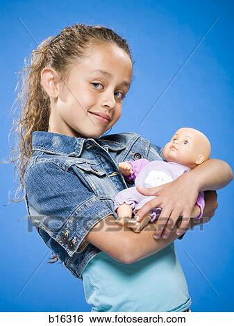 Girl holding baby doll smiling Stock Photograph | b16316 | Fotosearch