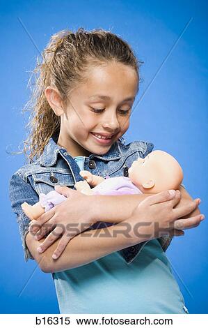 Girl holding baby doll smiling View Large Photo Image Stock Photography - Girl holding baby doll smiling. Fotosearch