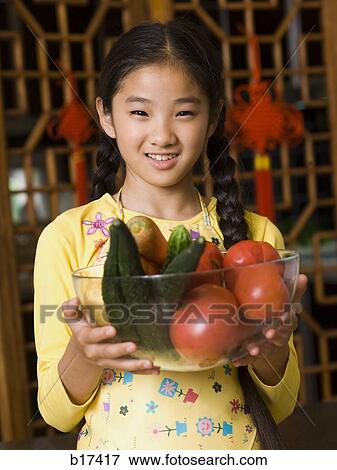 Girl holding bowl of vegetables smiling View Large Photo Image Stock Photo - Girl holding bowl of vegetables smiling. Fotosearch