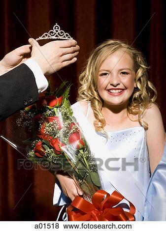 Girl holding red roses being crowned with tiara smiling View Large Photo Image Stock Photo - Girl holding red roses being crowned with tiara smiling. Fotosearch