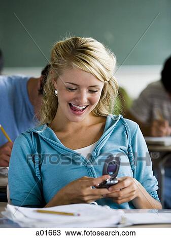 Girl looking at mobile phone in class. View Large Photo Image Stock Image - Girl looking at mobile phone in class.. Fotosearch