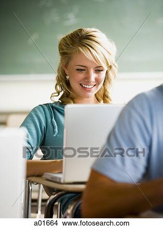 Girl looking at notebook computer in classroom. View Large Photo Image Picture - Girl looking at notebook computer in classroom.. Fotosearch