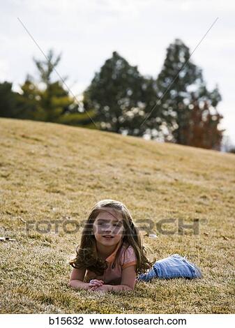 Girl lying down on grass outdoors View Large Photo Image Stock Image - Girl lying down on grass outdoors. Fotosearch