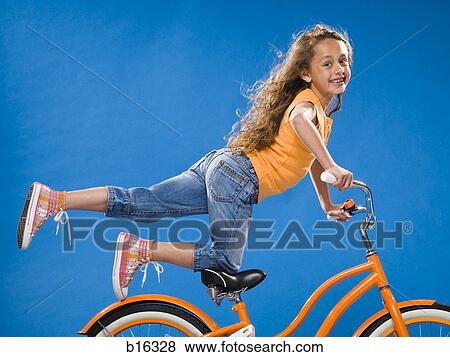 Girl on orange bicycle kneeling on seat with foot up View Large Photo Image Stock Photo - Girl on orange bicycle kneeling on seat with foot up. Fotosearch