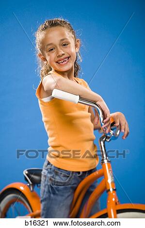 Girl on orange bicycle smiling View Large Photo Image Stock Image - Girl on orange bicycle smiling. Fotosearch