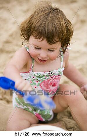 Girl on sandy beach with toy shovel View Large Photo Image Stock Photo - Girl on sandy beach with toy shovel. Fotosearch