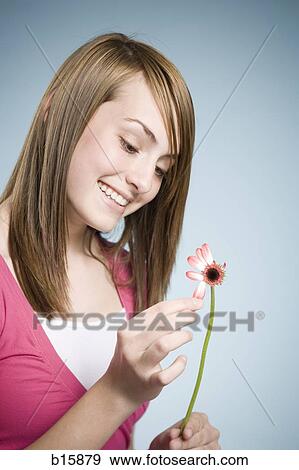 Stock Photo - Girl picking petals off flower smiling. Fotosearch