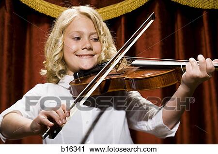 Stock Image - Girl playing violin on stage. Fotosearch