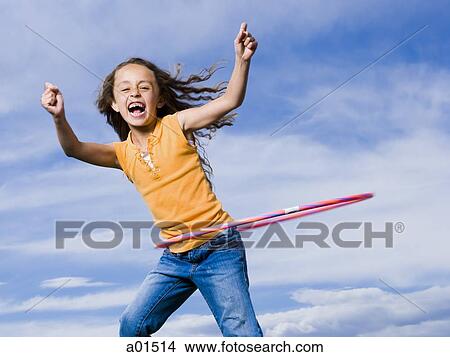 Picture - Girl playing with hula hoop outdoors laughing. Fotosearch