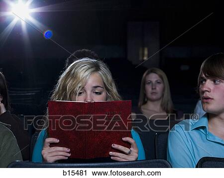 Girl reading hardcover book at movie theater View Large Photo Image Stock Image - Girl reading hardcover book at movie theater. Fotosearch