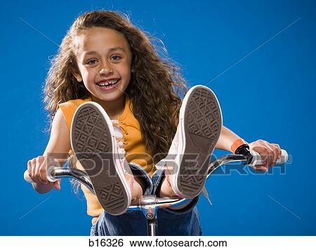 Stock Photograph - Girl riding bicycle with feet on handlebars. Fotosearch