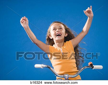 Picture - Girl riding bicycle with no hands smiling. Fotosearch