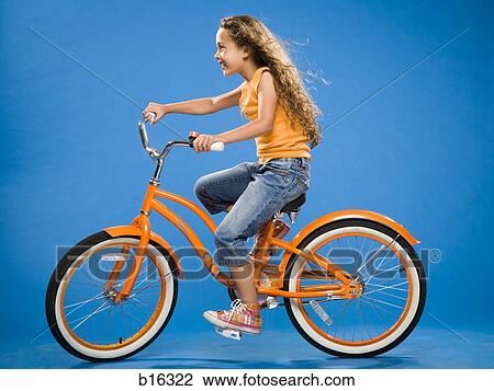 Stock Image - Girl riding orange bicycle profile. Fotosearch