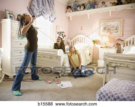 Girl singing into hairbrush in bedroom with girlfriends laughing View Large Photo Image Stock Photo - Girl singing into hairbrush in bedroom with girlfriends laughing. Fotosearch