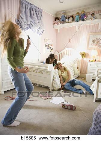Girl singing into hairbrush in bedroom with girlfriends laughing View Large Photo Image Stock Photography - Girl singing into hairbrush in bedroom with girlfriends laughing. Fotosearch