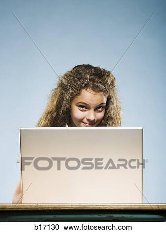 Girl sitting at desk with laptop View Large Photo Image Stock Image - Girl sitting at desk with laptop. Fotosearch