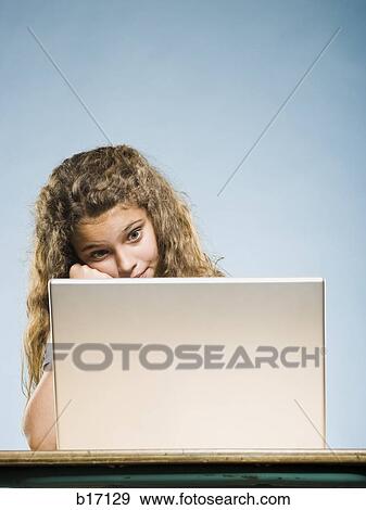 Girl sitting at desk with laptop View Large Photo Image Stock Photo - Girl sitting at desk with laptop. Fotosearch