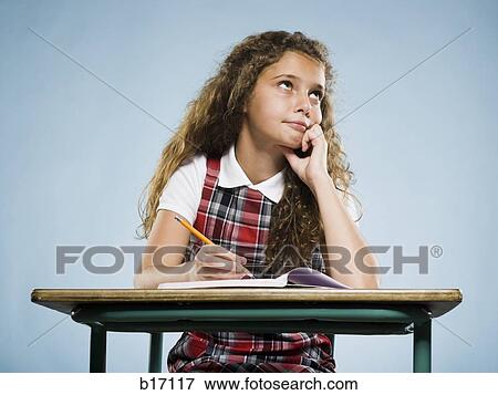 Stock Photo - Girl sitting at desk with workbook looking bored. Fotosearch