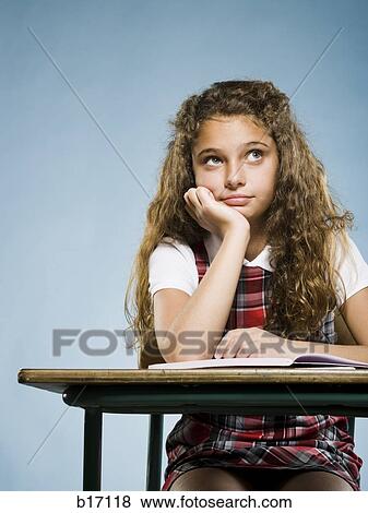 Stock Photo - Girl sitting at desk with workbook looking bored. Fotosearch