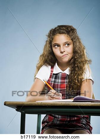 Girl sitting at desk with workbook concentrating View Large Photo Image Stock Photo - Girl sitting at desk with workbook concentrating. Fotosearch