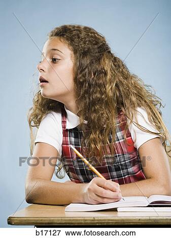 Girl sitting at desk with workbook looking over View Large Photo Image Stock Photo - Girl sitting at desk with workbook looking over. Fotosearch