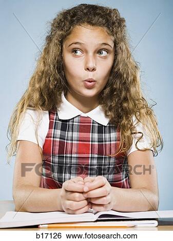 Stock Photograph - Girl sitting at desk with workbook. Fotosearch