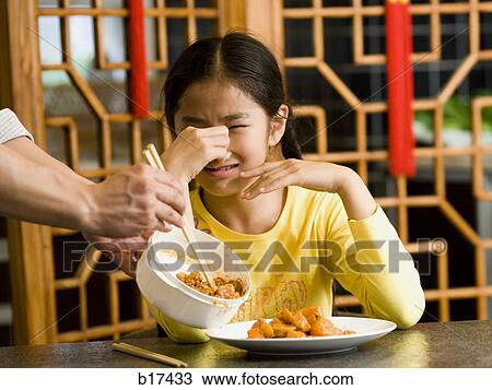 Girl sitting at table with food holding nose in disgust View Large Photo Image Stock Image - Girl sitting at table with food holding nose in disgust. Fotosearch