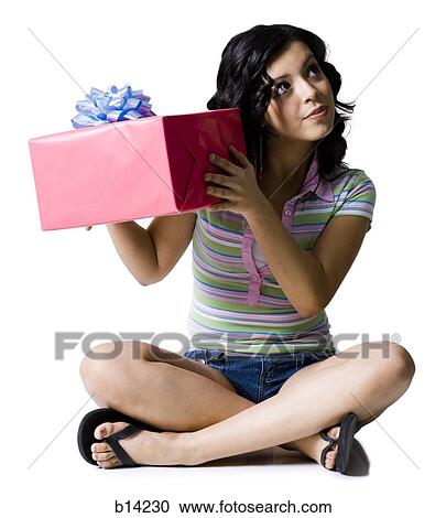 Stock Image - Girl sitting cross legged with gift box. Fotosearch