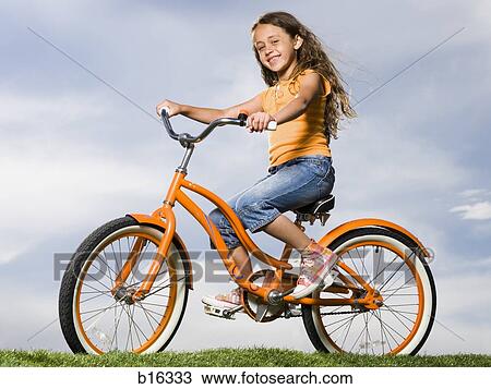 Girl sitting on orange bicycle outdoors smiling View Large Photo Image Stock Image - Girl sitting on orange bicycle outdoors smiling. Fotosearch