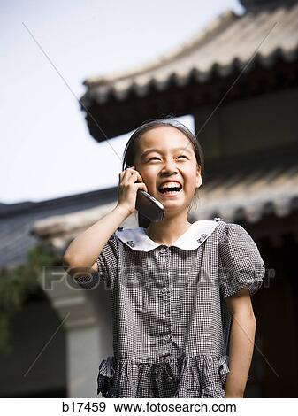 Girl standing outdoors with cell phone in front of pagoda smiling View Large Photo Image Stock Photo - Girl standing outdoors with cell phone in front of pagoda smiling. Fotosearch