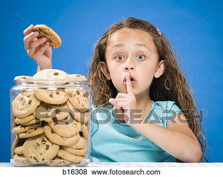Girl taking chocolate chip cookie from jar and hushing View Large Photo Image Stock Photo - Girl taking chocolate chip cookie from jar and hushing. Fotosearch