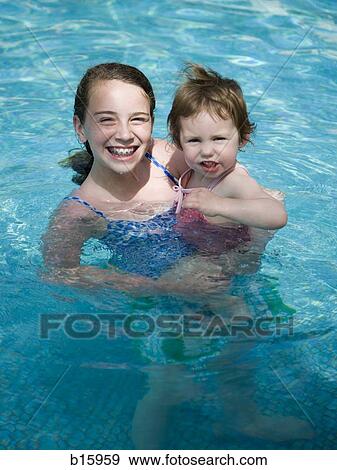 Girl with braces in pool holding younger girl smiling View Large Photo Image Stock Photo - Girl with braces in pool holding younger girl smiling. Fotosearch